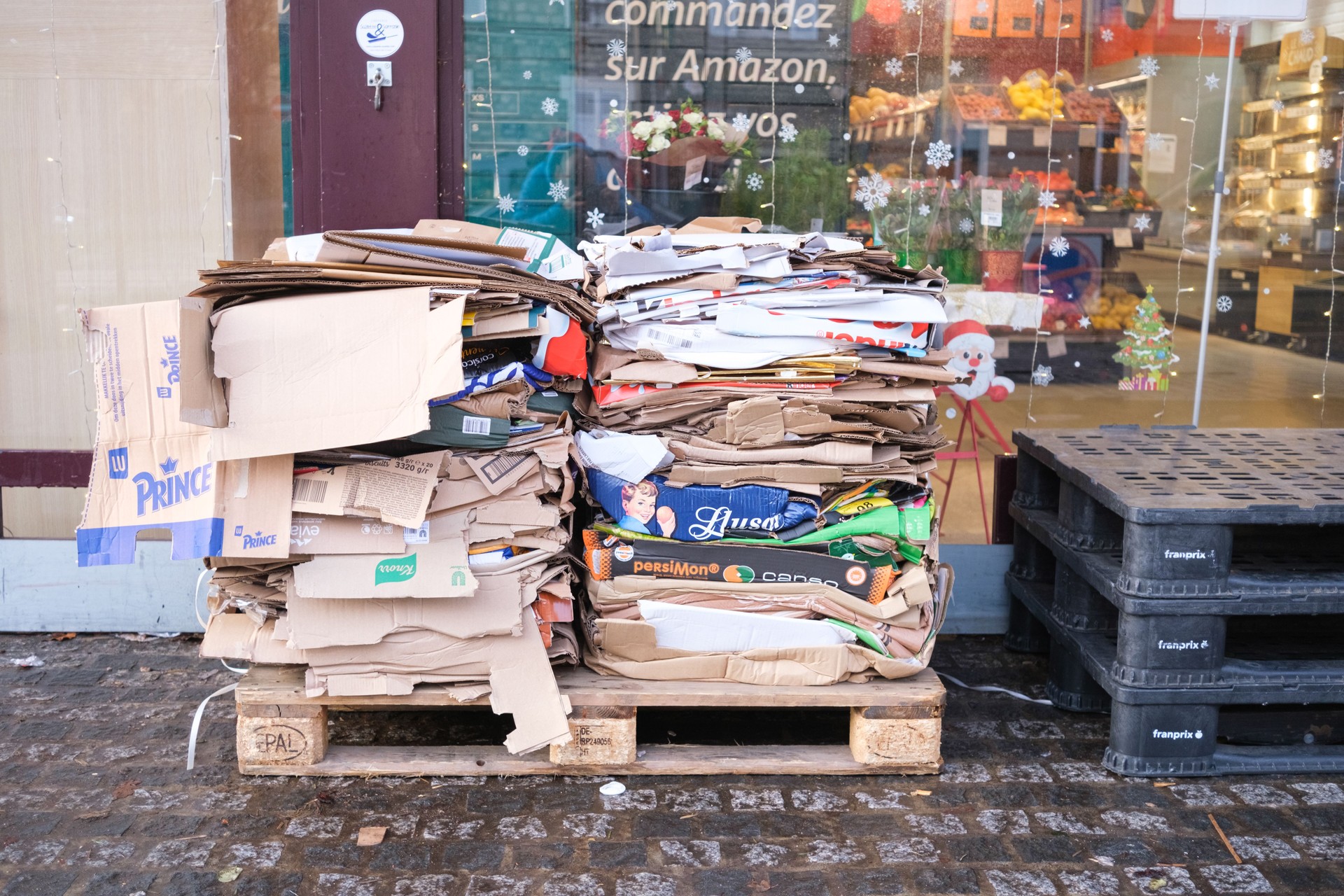 Des boîtes en carton, pliées et empilées pour être recyclées à la porte d’un supermarché.